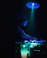 a woman djing in a dark room with blue lights